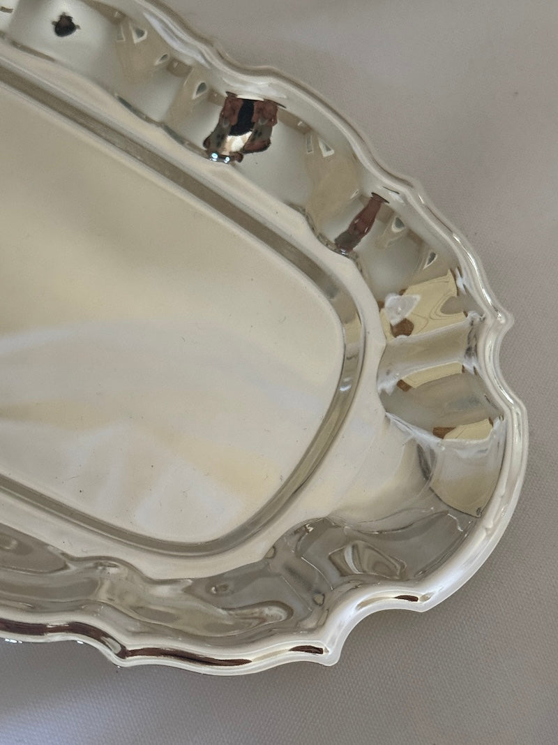 Silver tray with decorative edge on a light gray background