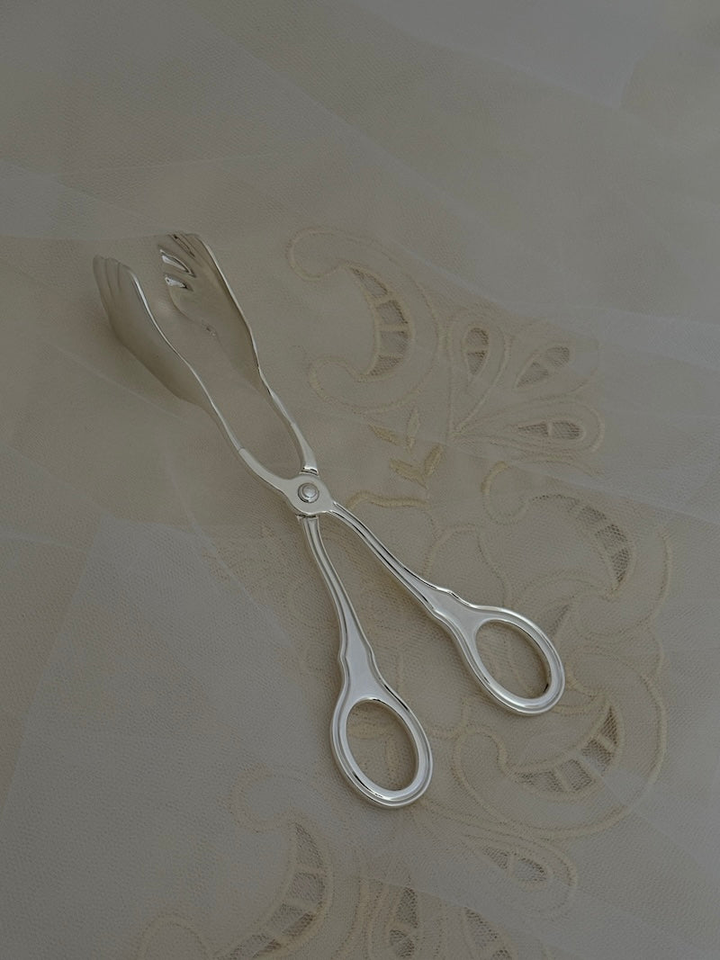 Silver tongs on a textured white surface