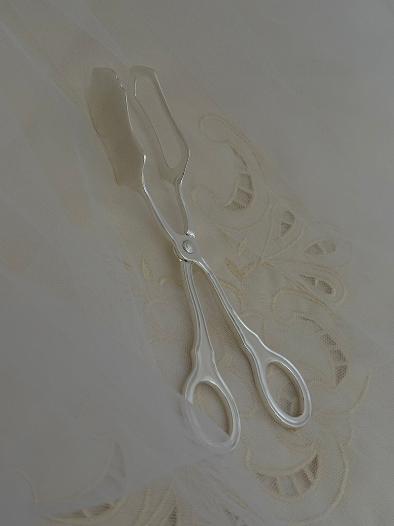 silver tongs against a textured white background