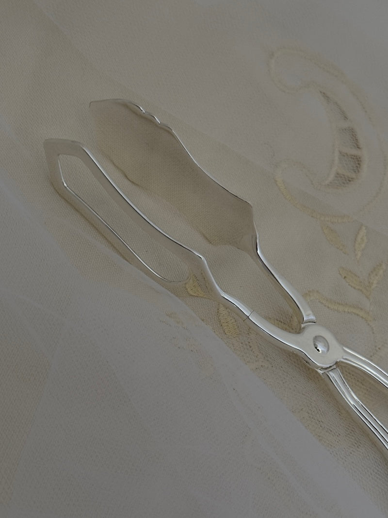 silver tongs against a textured white background