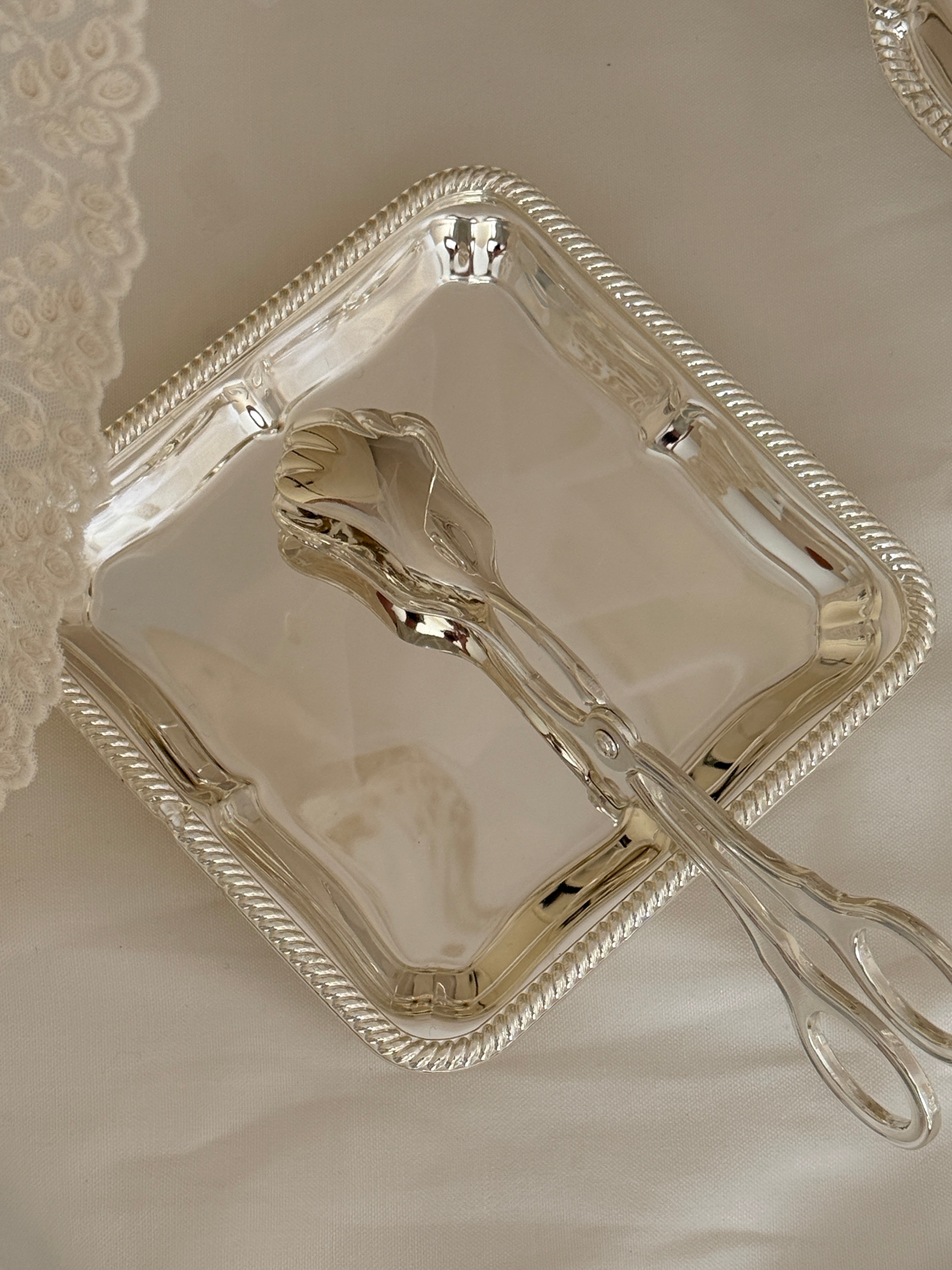 Silver serving tray with tongs on a textured surface