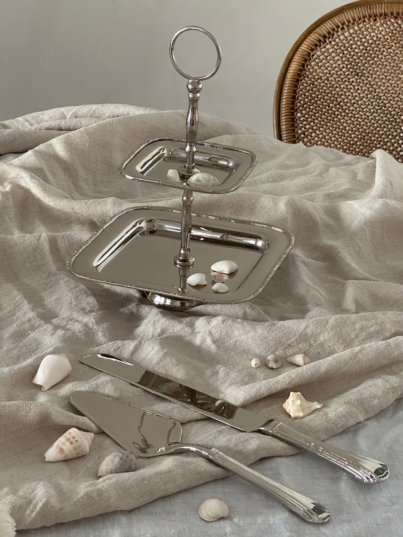 Silver cake stand with shell decorations on a textured surface