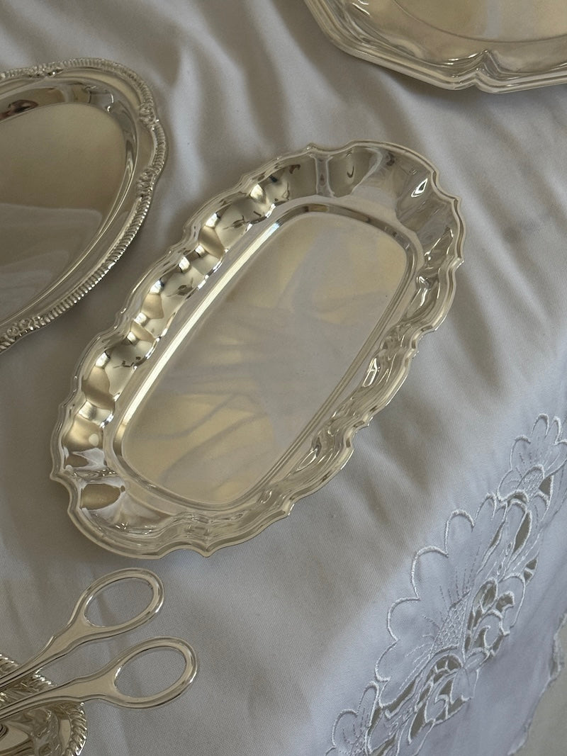 Silver trays and a pair of scissors on a white fabric background