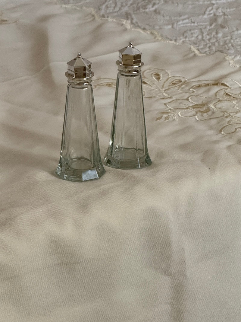 Two clear glass salt and pepper shakers on a textured surface