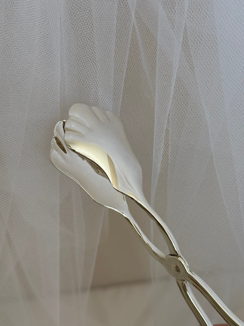 silver tongs  against a textured white background